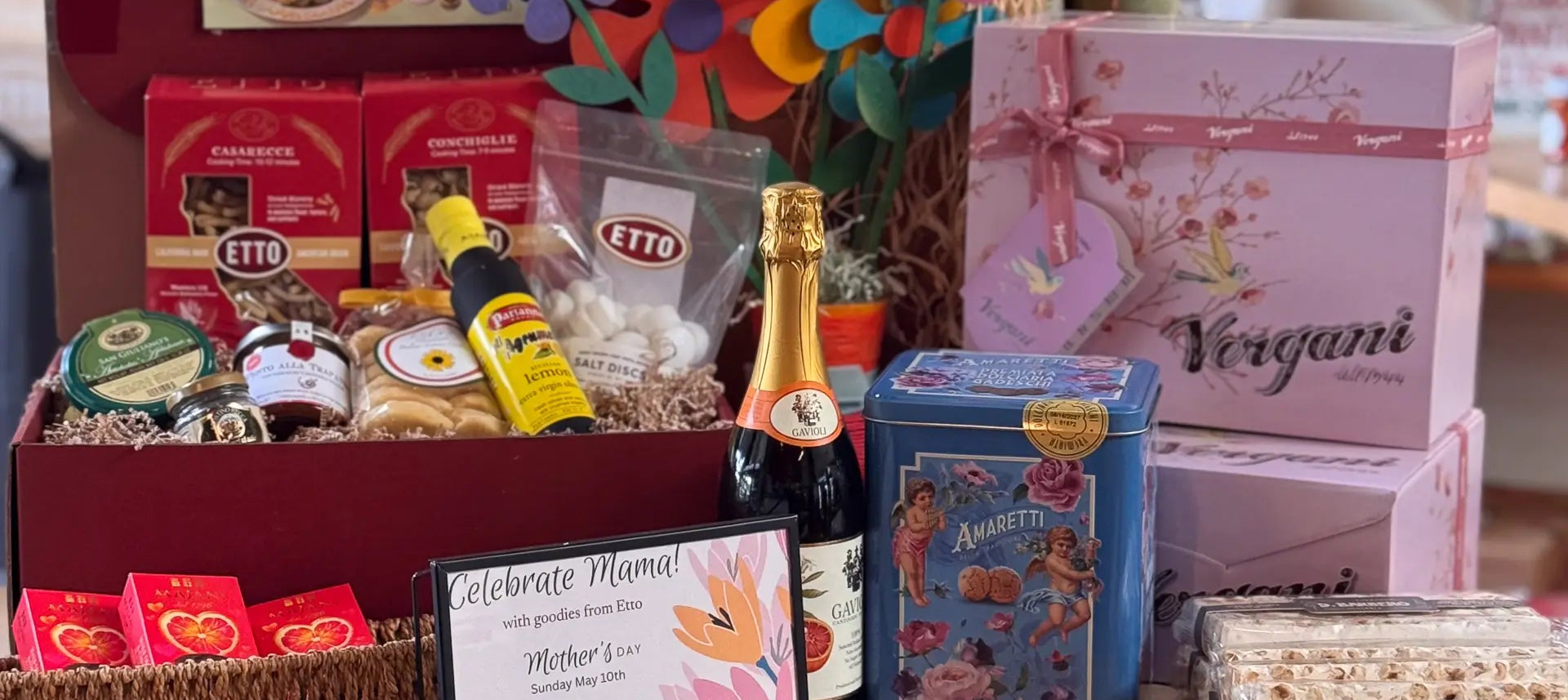 Gift basket with wine, snacks, and a card on a table.